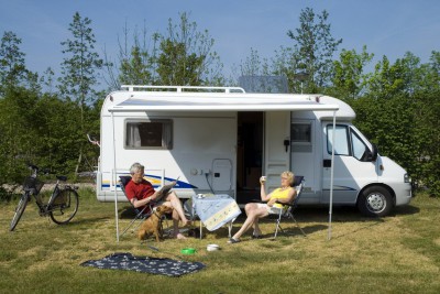 an elderly couple sitting in front of a camper